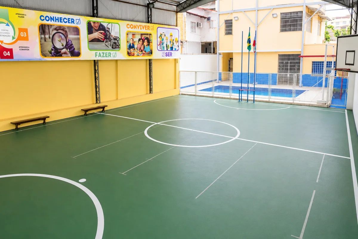 Quadra coberta com piscina ao fundo, no prédio do Fundamental I